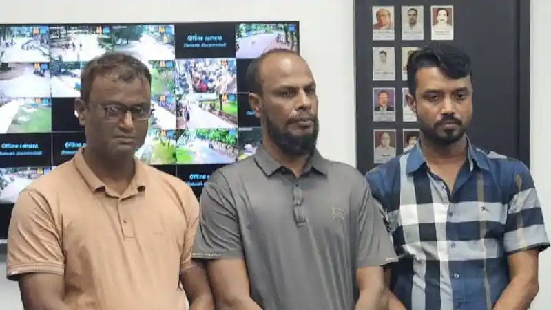 তিনজন ব্যক্তি দাঁড়িয়ে আছেন, পেছনে সিসিটিভি মনিটর দেখানো হচ্ছে. Channel i News - চ্যানেল আই নিউজ