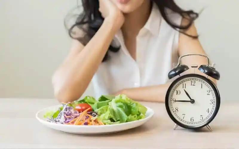 Healthy salad and alarm clock representing intermittent fasting benefits and timing. Channel i News - চ্যানেল আই নিউজ