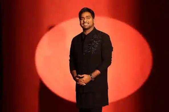 জাকির খান হাসিমুখে দাঁড়িয়ে, পটভূমিতে লাল আলো।. Channel i News - চ্যানেল আই নিউজ