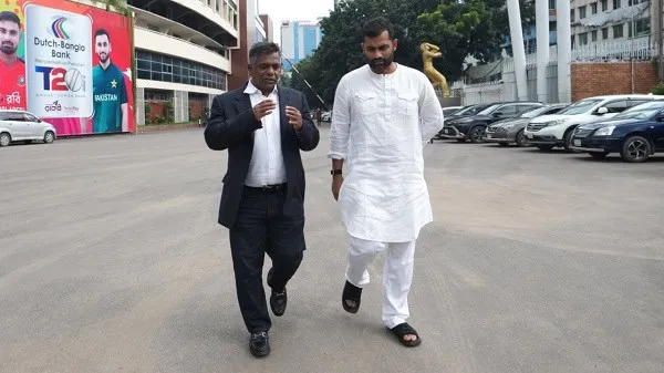 দুই ব্যক্তি শহরে হাঁটছেন, একজন স্যুট পরা ও অন্যজন পাঞ্জাবি পরা. Channel i News - চ্যানেল আই নিউজ