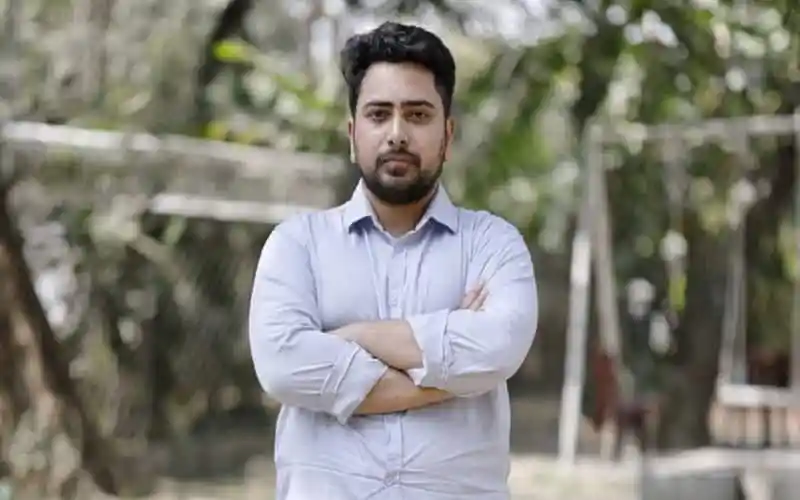 আত্মবিশ্বাসী যুবক, পটভূমিতে গাছপালা ও কাঠের বেড়া. Channel i News - চ্যানেল আই নিউজ