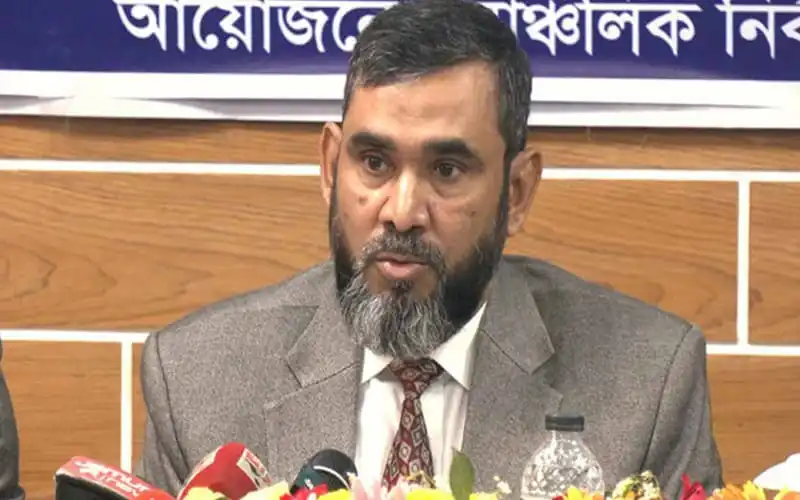 Bangladeshi man in formal suit speaking at a press conference. Channel i News - চ্যানেল আই নিউজ