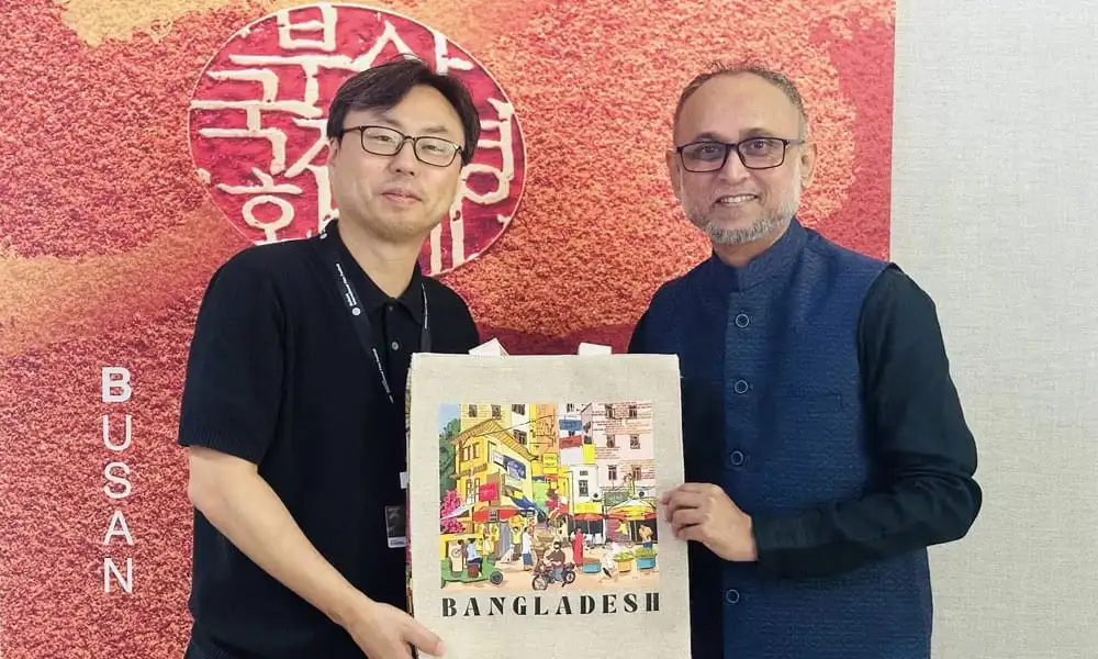 দুই ব্যক্তি বাংলাদেশের শিল্পের ছবি সহ একটি উপহার গ্রহণ করছেন. Channel i News - চ্যানেল আই নিউজ