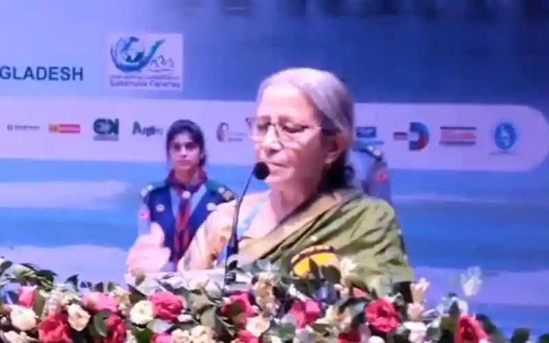 প্রধান অতিথি হিসেবে বক্তৃতা দিচ্ছেন একজন নারী, পেছনে শিশু ও বিভিন্ন লোগো দেখা যাচ্ছে. Channel i News - চ্যানেল আই নিউজ