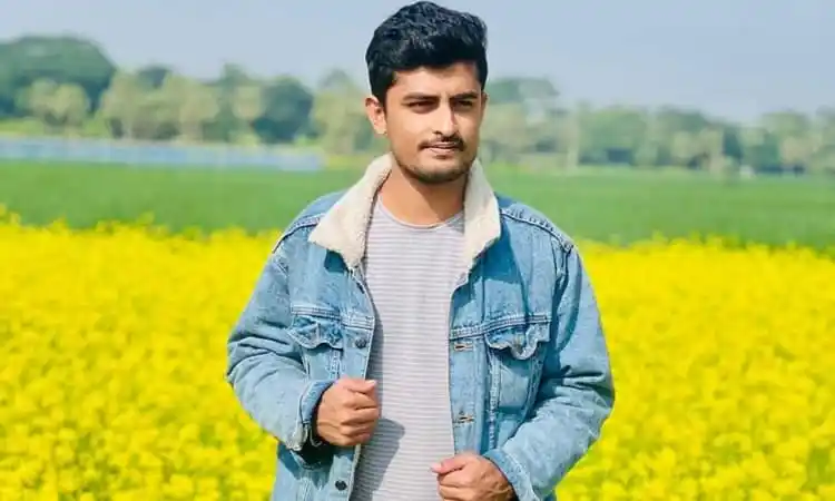 Young man standing in a yellow flower field in Bangladesh. Channel i News - চ্যানেল আই নিউজ