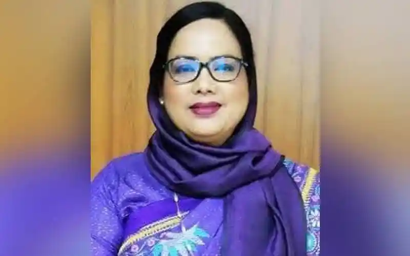 বাংলাদেশের একজন নারী কর্মকর্তা, পর্দার পেছনে দাঁড়িয়ে হাসছেন।. Channel i News - চ্যানেল আই নিউজ
