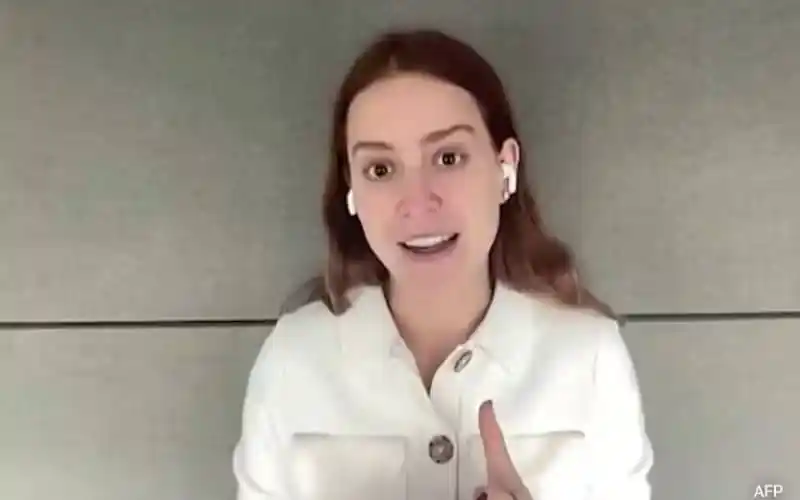 Woman speaking during a virtual interview, wearing white shirt and AirPods. Channel i News - চ্যানেল আই নিউজ
