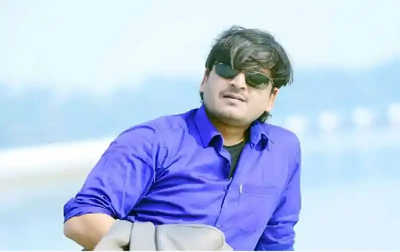 নদীর পাশে যুবক সেলফি তোলার ছবি, কালো চশমা পরা, ব্লু শার্টে. Channel i News - চ্যানেল আই নিউজ