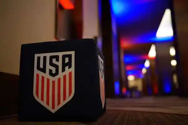 USA soccer team logo on a black cube with colorful background. Channel i News - চ্যানেল আই নিউজ