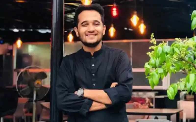স্মিত হাসি সহ যুবক ব্যক্তি ক্যাফে বা রেস্টুরেন্টে দাঁড়িয়ে. Channel i News - চ্যানেল আই নিউজ