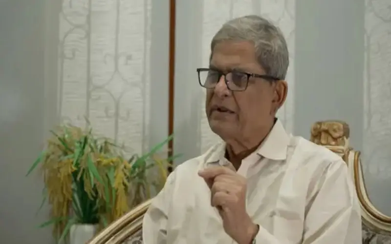 বয়স্ক ব্যক্তি বক্তৃতা দিচ্ছেন, পটভূমিতে গাছের পাতা ও আসবাবপত্র. Channel i News - চ্যানেল আই নিউজ