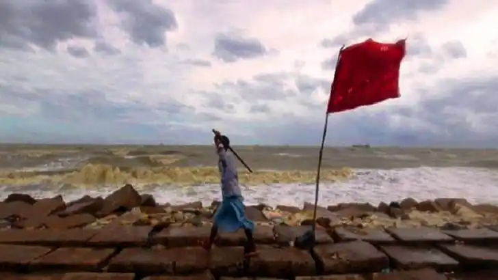 চট্টগ্রাম উপকূলে ঝড়ের সতর্কতা সংকেত দেখাচ্ছে একজন ব্যক্তি. Channel i News - চ্যানেল আই নিউজ