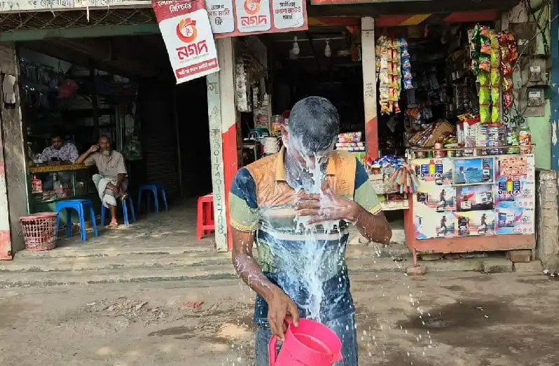 দুধ দিয়ে গোসল করছে একজন ব্যক্তি, পেছনে দোকান ও গ্রাহকরা।. Channel i News - চ্যানেল আই নিউজ