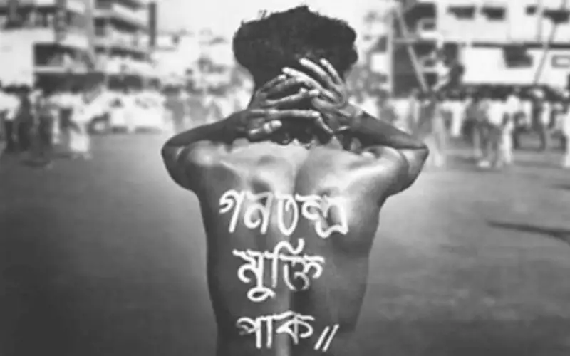 শহীদ নূর হোসেনের স্মরণে ব্যথিত যুবক, পিঠে লেখা বাংলায়. Channel i News - চ্যানেল আই নিউজ