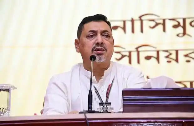 বাংলাদেশের একজন নেতা ভাষণ দিচ্ছেন, পত্রপাঠের পেছনে বাংলা লেখা. Channel i News - চ্যানেল আই নিউজ