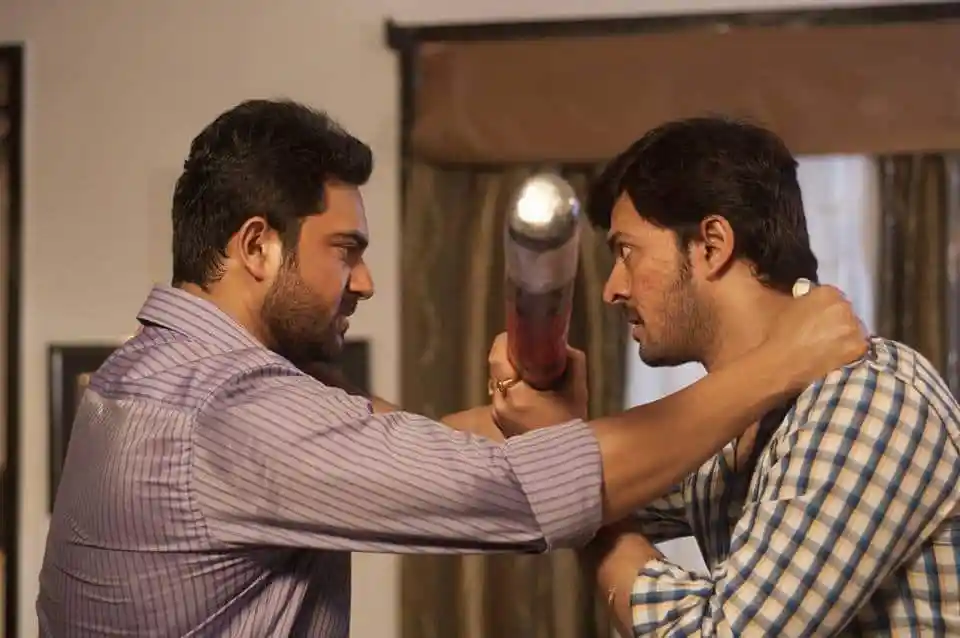 অভিনেতা স্টুডিও সেটে বসে, পেছনে ক্যামেরা ও আলো সরঞ্জাম. Channel i News - চ্যানেল আই নিউজ