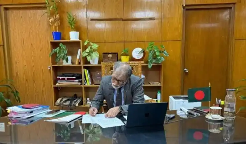 সায়েদুর রহমান অফিসে বসে কাজ করছেন, বাংলাদেশ পতাকা পাশে. Channel i News - চ্যানেল আই নিউজ