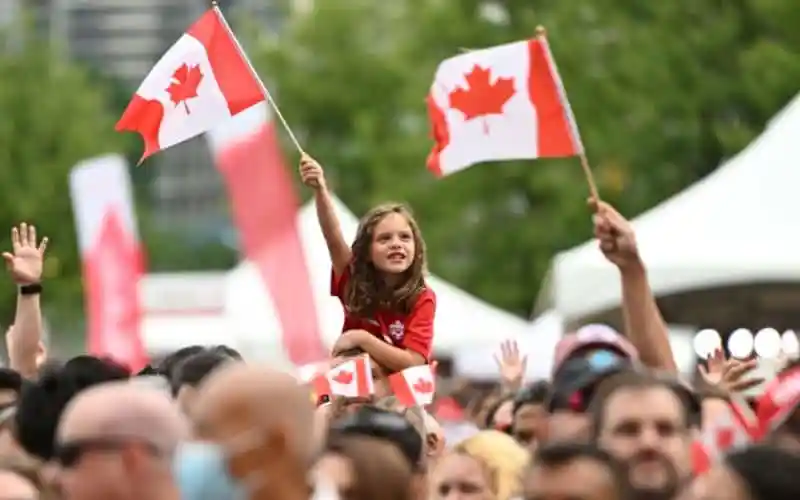 Canadian flags waved by children at a public event in Canada. Channel i News - চ্যানেল আই নিউজ