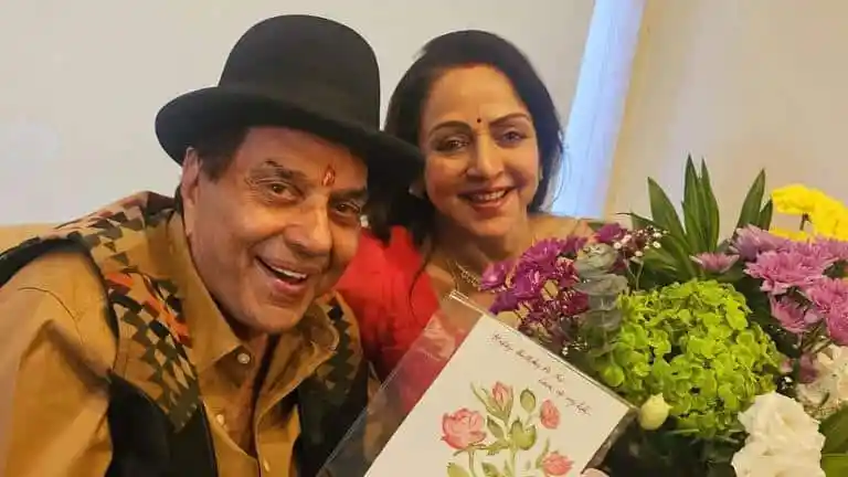দুজন ব্যক্তি হাস্যোজ্জ্বল মুখে ফুলের পাশে ছবি তুলছেন।. Channel i News - চ্যানেল আই নিউজ
