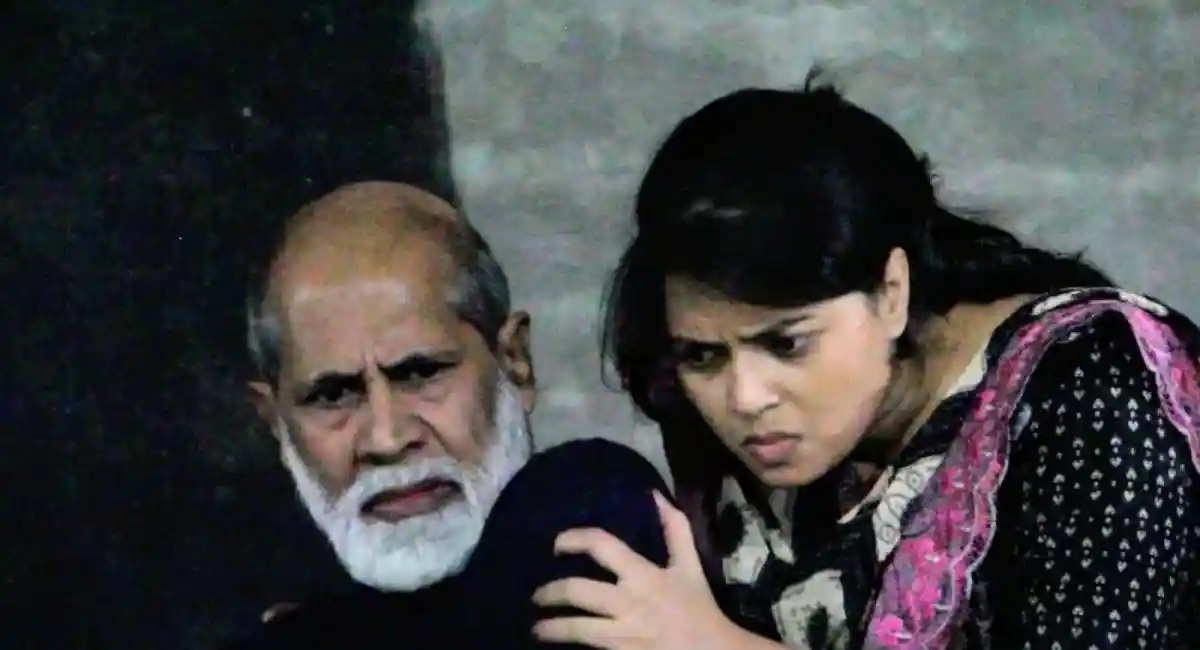 দর্শকরা নাটকের দৃশ্য দেখছেন, দুই অভিনেতা মনোযোগে অভিনয় করছেন. Channel i News - চ্যানেল আই নিউজ