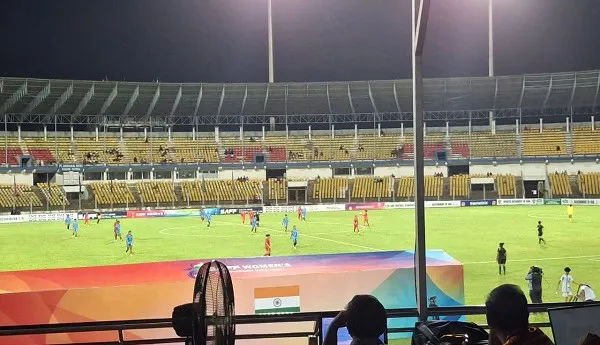 ভারত ও বাংলাদেশের ফুটবল দল মাঠে খেলছে, দর্শকরা স্ট্যান্ডে বসে দেখছেন. Channel i News - চ্যানেল আই নিউজ