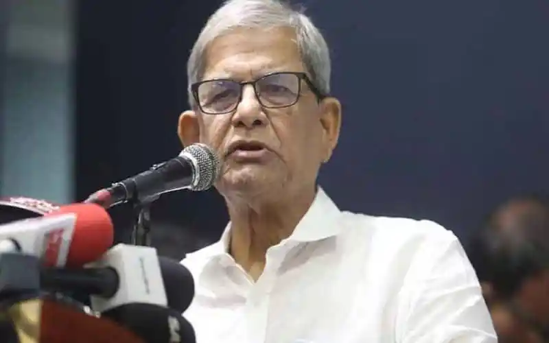 প্রধান বক্তা speaking at a press conference with microphones in front. Channel i News - চ্যানেল আই নিউজ