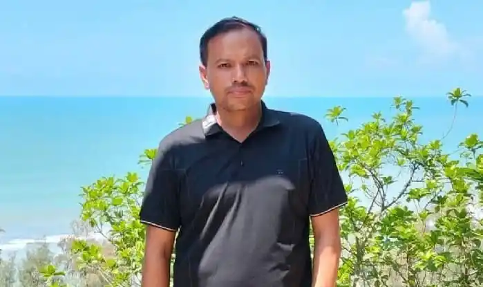 Man standing outdoors near the sea with green plants in the background. Channel i News - চ্যানেল আই নিউজ