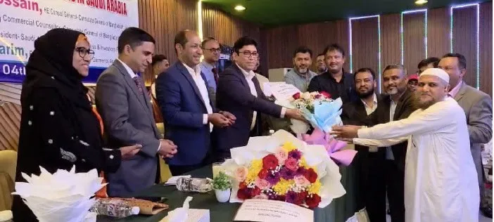 Bangladeshi officials and guests celebrate at a formal event with flowers and handshakes. Channel i News - চ্যানেল আই নিউজ
