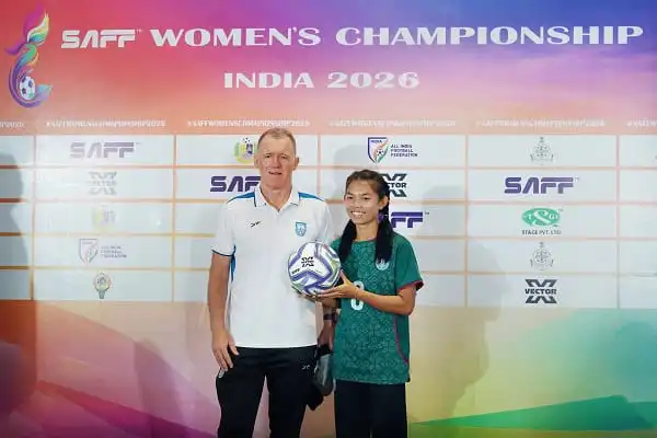 একজন মহিলা ফুটবল খেলোয়াড় পুরস্কার গ্রহণ করছেন, পাশে একজন পুরুষ কোচ বা কর্মকর্তা. Channel i News - চ্যানেল আই নিউজ