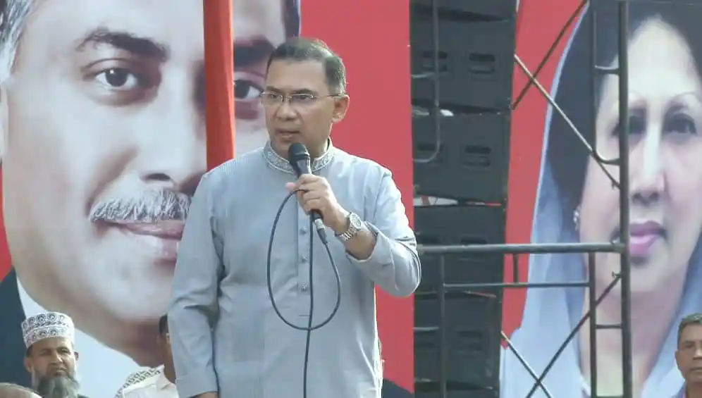 জনপ্রিয় নেতা জনসভায় বক্তব্য দিচ্ছেন, পেছনে বড় ছবি ও নেত্রীর ছবি।. Channel i News - চ্যানেল আই নিউজ