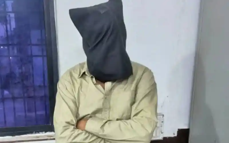 অজ্ঞাত ব্যক্তি মুখোশ পরা, হাত ঝুলানো, সাদা দেয়ালে দাঁড়িয়ে. Channel i News - চ্যানেল আই নিউজ