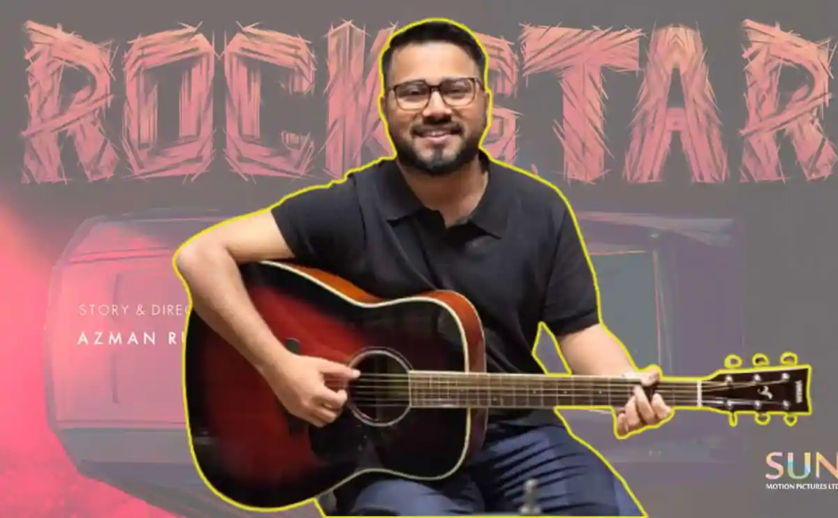 গিটার বাজাচ্ছেন একজন মিউজিশিয়ান, পেছনে রকেটের ছবি ও লেখনী. Channel i News - চ্যানেল আই নিউজ