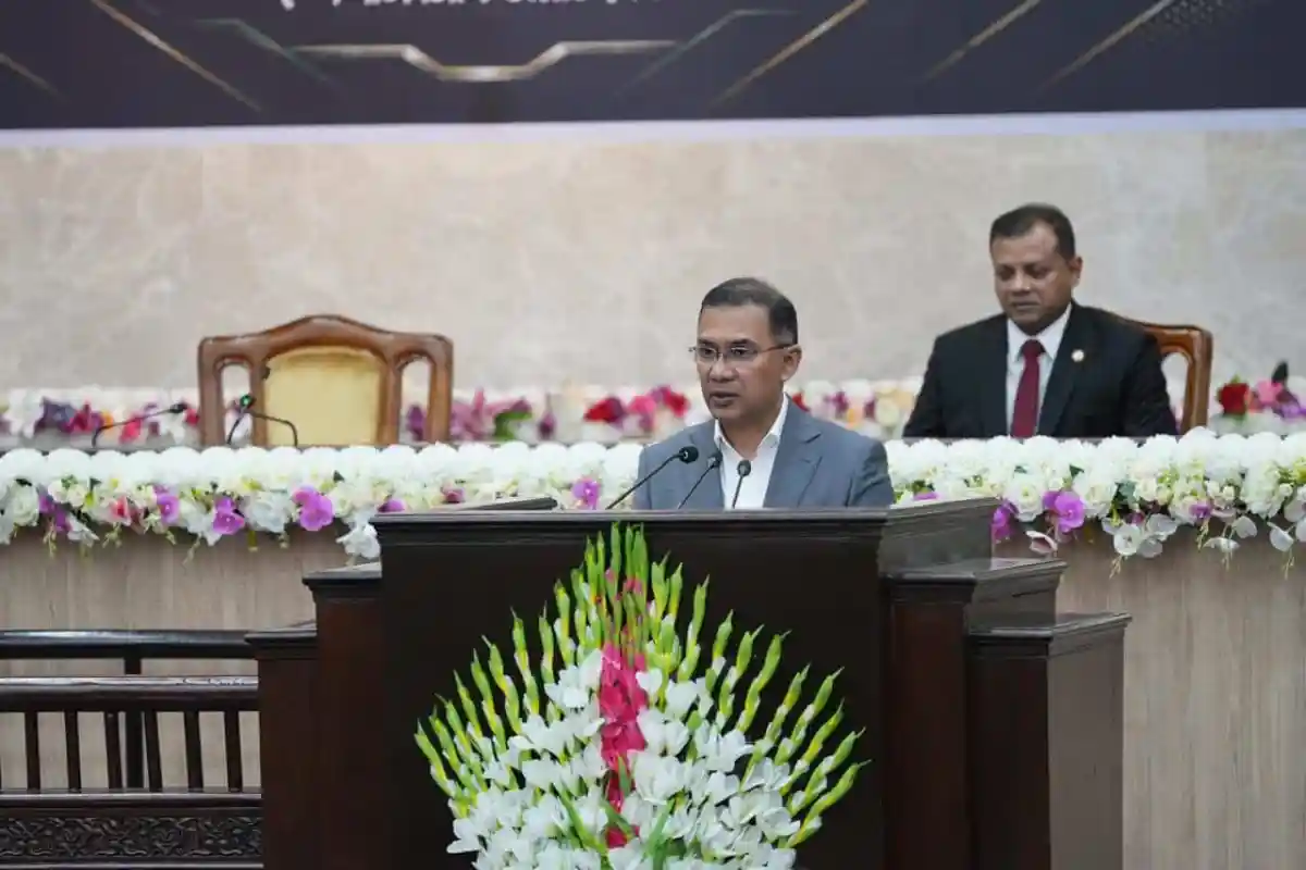 প্রধানমন্ত্রী বক্তৃতা দিচ্ছেন, পেছনে অন্য একজন বসে আছেন. Channel i News - চ্যানেল আই নিউজ
