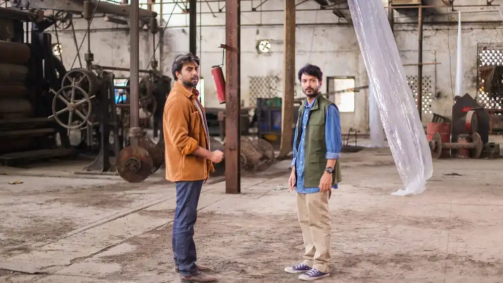 দুটি যুবক কারখানার ভেতরে কথা বলছেন, শিল্পকারখানা পরিবেশে।. Channel i News - চ্যানেল আই নিউজ