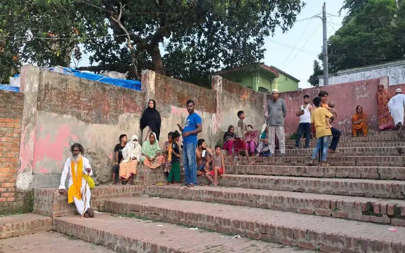 Bangladeshi people gather on outdoor stairs in a community setting. Channel i News - চ্যানেল আই নিউজ