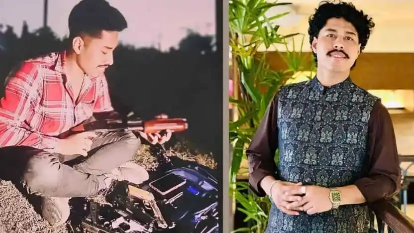 Young man sitting outdoors with a guitar, wearing a red checkered shirt. Channel i News - চ্যানেল আই নিউজ