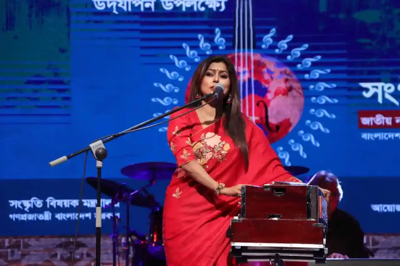 বাংলাদেশি সংগীতশিল্পী সংগীত পরিবেশন করছেন, লাল শাড়ি পরা. Channel i News - চ্যানেল আই নিউজ