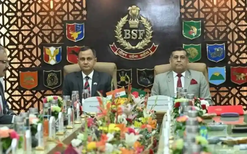 বাংলাদেশের দুই পুলিশ কর্মকর্তা বৈঠকে বসে, পেছনে ব্যানার ও পতাকা. Channel i News - চ্যানেল আই নিউজ