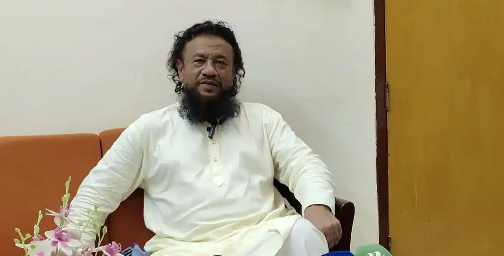 বাংলাদেশের একজন রাজনীতিবিদ বসে আছেন, পটভূমিতে সাদা দেয়াল. Channel i News - চ্যানেল আই নিউজ
