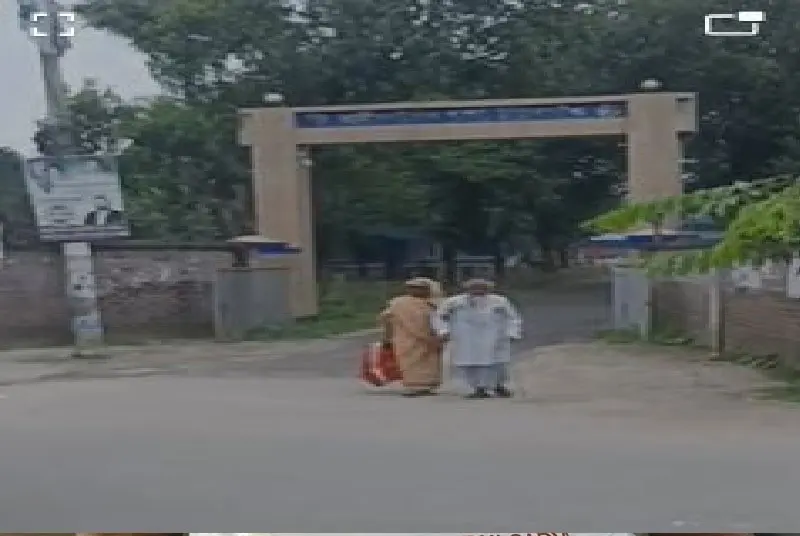 Two elderly men sitting on the road near an entrance gate in Thakurgaon. Channel i News - চ্যানেল আই নিউজ