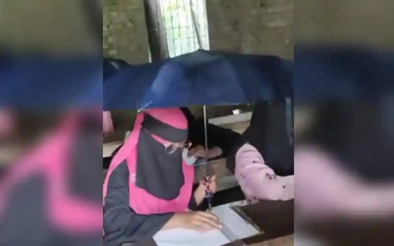 বৃষ্টিতে পরীক্ষার হলে শিক্ষার্থীরা এক হাতে কলম অন্য হাতে ছাতা ধরে বসে।. Channel i News - চ্যানেল আই নিউজ
