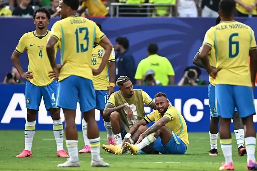 Brazilian football players on the field after a match, some sitting and some standing. Channel i News - চ্যানেল আই নিউজ