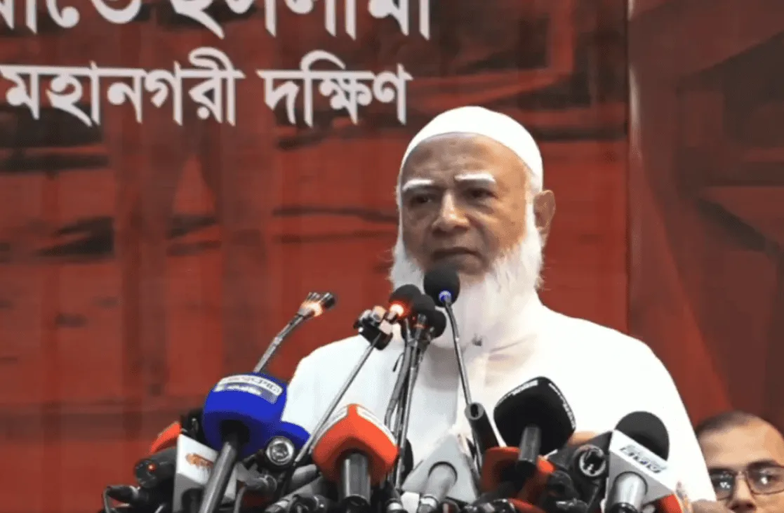 জামায়াত আমিরের বক্তৃতা, পেছনে লাল ব্যাকড্রপ ও মাইক্রোফোনের মঞ্চ. Channel i News - চ্যানেল আই নিউজ