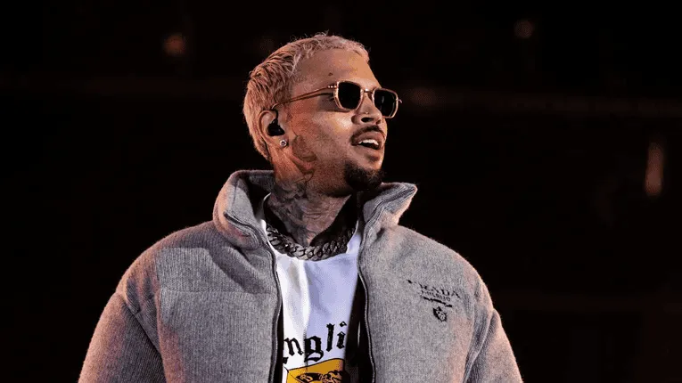 Rapper with sunglasses and tattoos performing on stage at night. Channel i News - চ্যানেল আই নিউজ