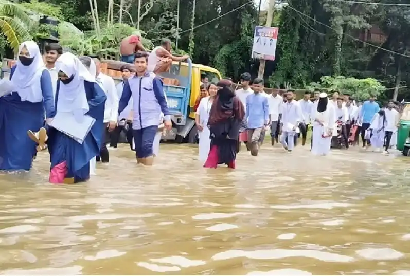 শিক্ষার্থীরা বন্যার পানিতে হাঁটছে, স্কুলের ছাত্র-ছাত্রীদের ছবি।. Channel i News - চ্যানেল আই নিউজ