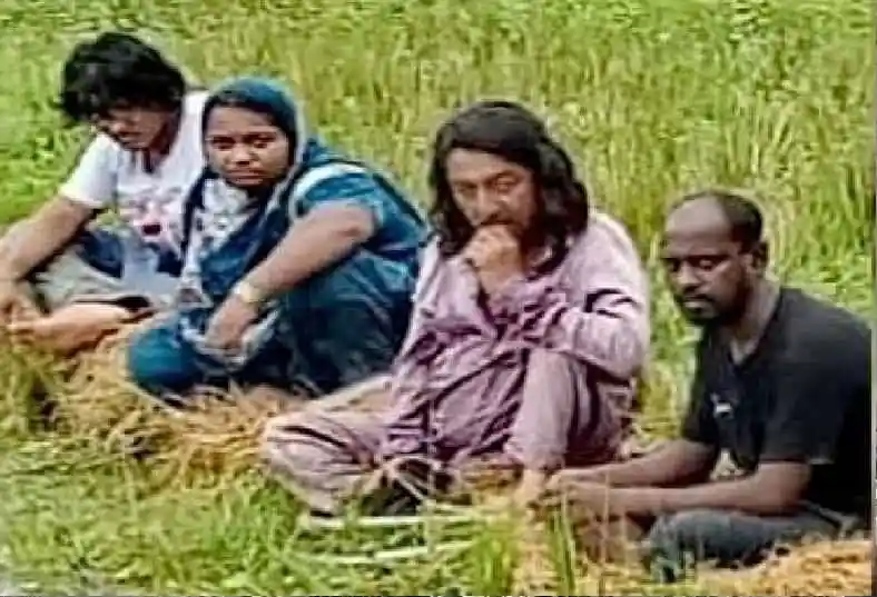 Four people sitting on a grassy field near the border. Channel i News - চ্যানেল আই নিউজ