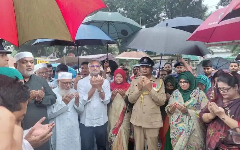 জনতা ও পুলিশ সদস্যরা জলবৃষ্টির মধ্যে গণঅভ্যুত্থান দিবসের প্রার্থনা করছেন. Channel i News - চ্যানেল আই নিউজ