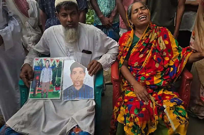 দুজন ব্যক্তি তাদের প্রিয়জনের ছবি দেখছেন, শোকাহত পরিবার।. Channel i News - চ্যানেল আই নিউজ