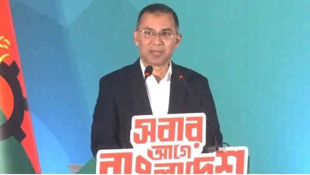 বাংলাদেশের প্রধানমন্ত্রী শেখ হাসিনা ভাষণ দিচ্ছেন, পেছনে বাংলাদেশ পতাকা. Channel i News - চ্যানেল আই নিউজ
