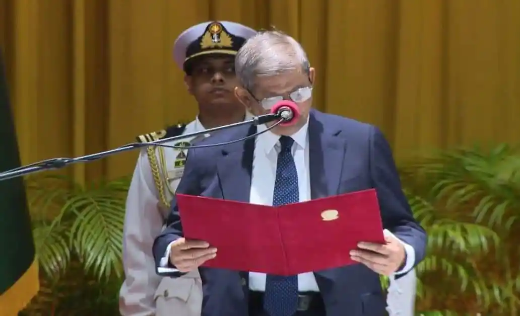 প্রধানমন্ত্রী শপথবাক্য পাঠ করছেন, পাশে নিরাপত্তা কর্মকর্তা উপস্থিত।. Channel i News - চ্যানেল আই নিউজ